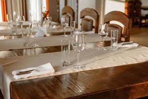Glasses, flower fork, knife served for dinner in restaurant with cozy interior photo
