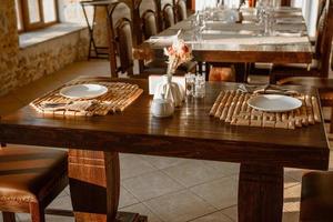 Glasses, flower fork, knife served for dinner in restaurant with cozy interior photo