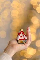 decoración del árbol de navidad en forma de casa en una hermosa mano femenina foto