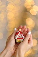 Christmas tree decoration in the shape of a house in a beautiful female hand photo