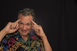 Dramatic Portrait of a Mature Man against a Black Background wearing a Colorful Shirt photo