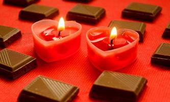 Two love burning hearts with chocolate bars on red background.