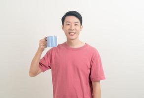 young Asian man holding coffee cup photo