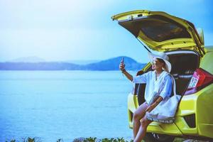 naturaleza de viaje de mujer asiática. viajar relajarse. sentado en el auto foto