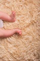 Bare legs of a newborn on a fluffy, light, one-ton, warm covering. Cute newborn baby feet close up photo