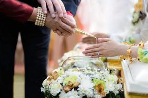 Holy water pouring ceremony over bride and groom hands, Thai traditional wedding engagement photo