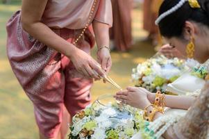 Holy water pouring ceremony over bride and groom hands, Thai traditional wedding engagement photo