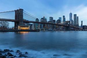 Brooklyn Bridge in Manhattan downtown with Cityscape on a foggy cloudy day at sunset New York USA