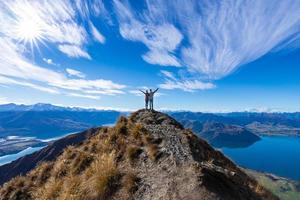Joven pareja asiática celebrando el éxito en roy's Peak Lake Wanaka, Nueva Zelanda