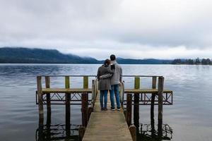 Joven pareja asiática abrazándose recostada sobre el hombro en el puente del lago Te Anau Nueva Zelanda foto