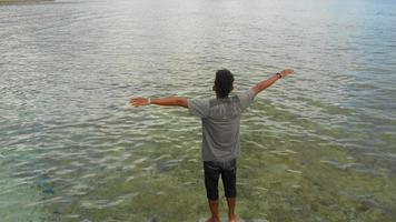 a man standing on a rock while enjoying the beauty of the beach. the concept of freedom photo