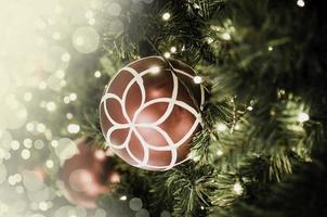 Closeup of red bauble hanging from a decorated Christmas tree. Retro filter effect. photo