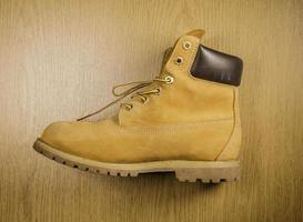 Pair of old yellow working boots Isolated on wood background photo