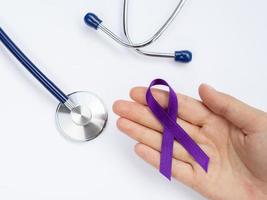 close up hand holding purple ribbon with stethoscope