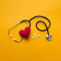 high angle view stethoscope stitched heart medicines yellow backdrop photo
