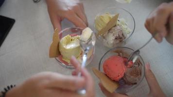 três garotas tomando sorvete com uma colher em um copo de vidro