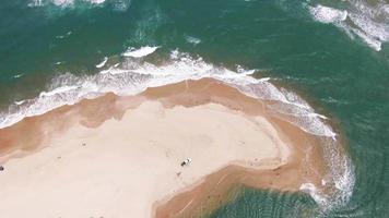 Aerial view of waves breaking on the beach and a car parked on the beach video