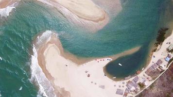 Vista aérea del mar encontró el río con gente divirtiéndose en la arena de la playa. video