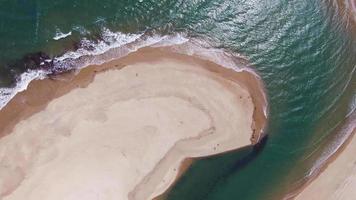imagens aéreas do drone da água da praia passando por um corredor de areia