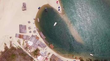 Vista aérea de barcos amarrados en la playa y algunas personas divirtiéndose en la arena video