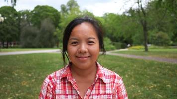 vue de face d'une femme asiatique heureuse debout et souriante dans le parc. se reposer avec une bonne nature. faire une promenade matinale le week-end. concept de pique-nique video