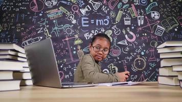 pigra bambina asiatica che gioca al videogioco durante la lezione online nella stanza di lavoro a casa. mettere il laptop sul tavolo e studiare il concetto online video