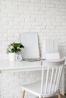 Front view of desk arrangement with blank calendar for mock up, paper folders and white frame with copy space photo