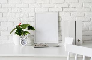 Front view of desk arrangement with blank calendar for mock up, paper folders and white frame with copy space photo