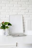 Front view of desk arrangement with blank calendar for mock up, paper folders and white frame with copy space photo