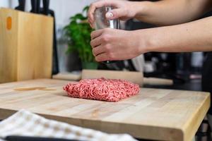 Beef seasoning person on a wooden table. Preparation of the meal. photo