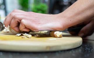A person crushing garlic with a knife. Preparation of the meal. photo