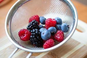 Raspberries, blueberries, blackberries in a strainer. photo