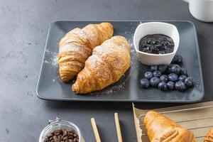 Delicious blueberry croissants on a dark plate. French breakfast. photo