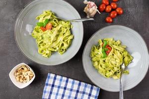 Italian pasta with delicious basil pesto in gray bowls. Top view.