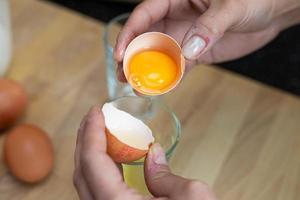 Separating the yolk from the egg white. Preparation of the dish in the kitchen. Visible hands. photo