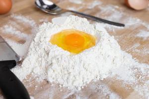 un huevo roto sobre un montón de harina. preparación de pasta casera. foto