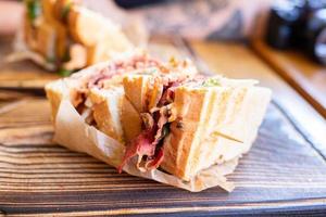 A crispy sandwich with meat and other toppings lying on a restaurant table. photo