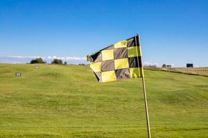 A checkered flag on a golf course signifying a hole photo