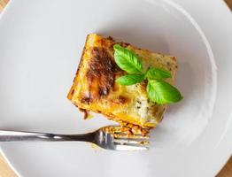 A piece of Italian lasagne on a white plate. Close-up top view. photo