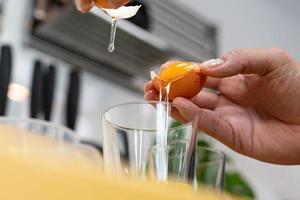 Breaking an egg into a container. Preparation of an Italian dish. Visible hands. photo
