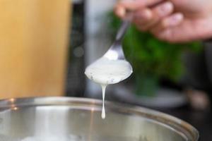 Bechamel sauce dripping from the kitchen spoon photo