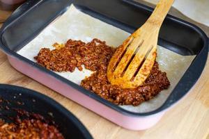 poner carne con salsa de tomate encima de la capa de pasta. preparación de lasaña.