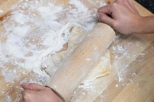 una persona enrollando la masa para hacer pasta de lasaña casera. foto