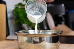 Pouring milk into a pot. Preparation of bechamel sauce. photo