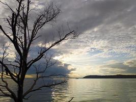 Puesta de sol y nublado en la bahía de Kariangau, Indonesia foto