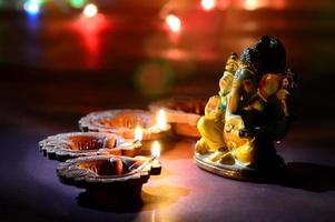 Clay diya lamps lit with Lord Ganesha during Diwali Celebration. Greetings Card Design Indian Hindu Light Festival called Diwali photo