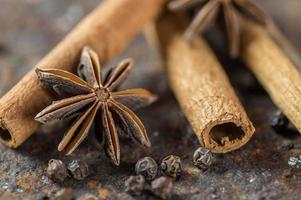 Palitos de canela, estrellas de anís y granos de pimienta negra sobre fondo de textura foto