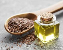 Flax seeds or linseeds in spoon and bowl with glass of linseed oil photo