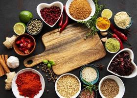 Various spices in a bowls and empty cutting board on black concrete background. Top view copy space. photo
