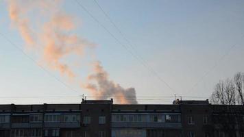 la fumée s'élève de la cheminée de la chaufferie au-dessus du bâtiment résidentiel video